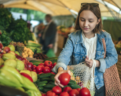 Teenager holding ecologically friendly reusable bag with fruit and vegetables