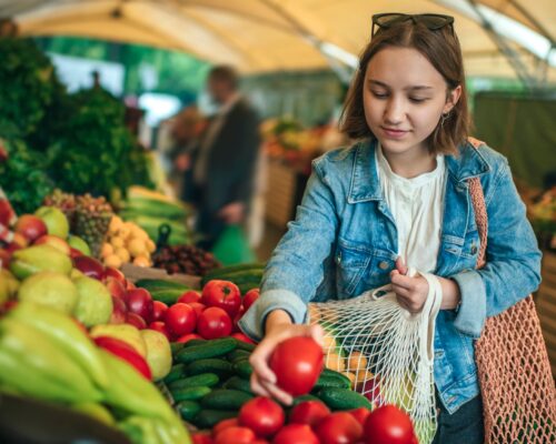 Teenager holding ecologically friendly reusable bag with fruit and vegetables